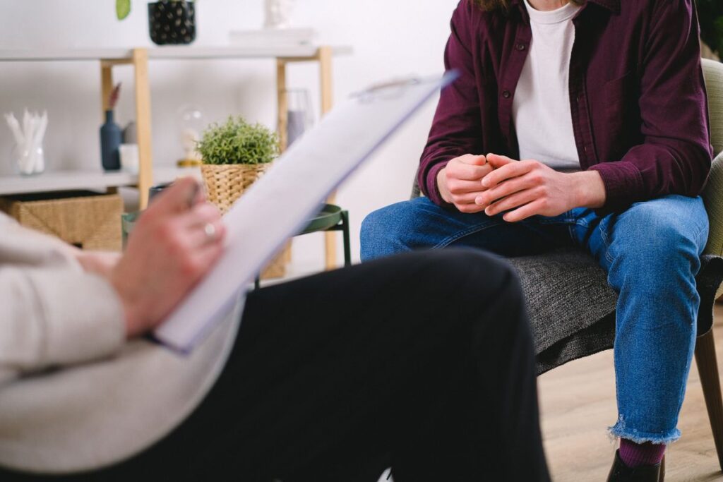 Therapist holds a clipboard while a client sits in a counseling session