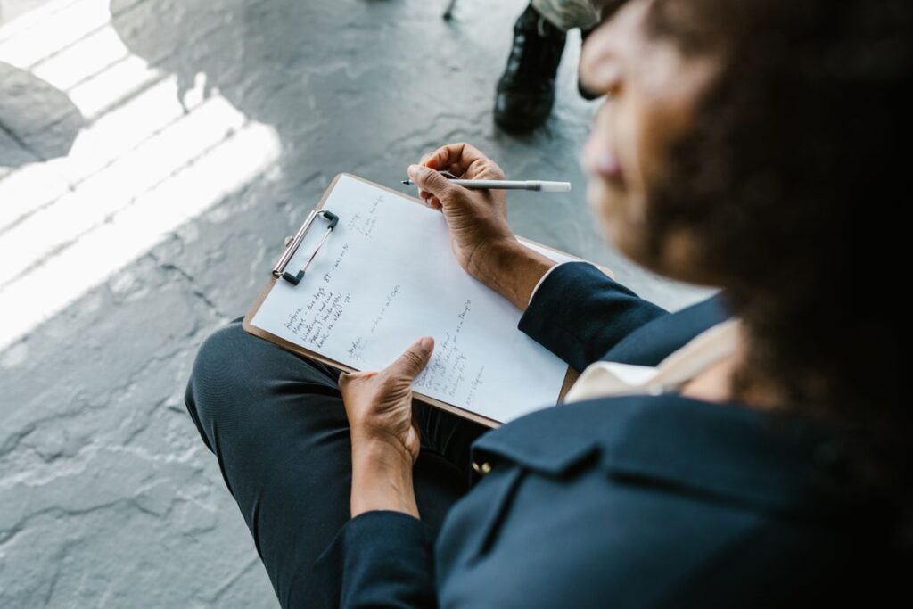 Clinician writing on a clipboard while reviewing therapy notes