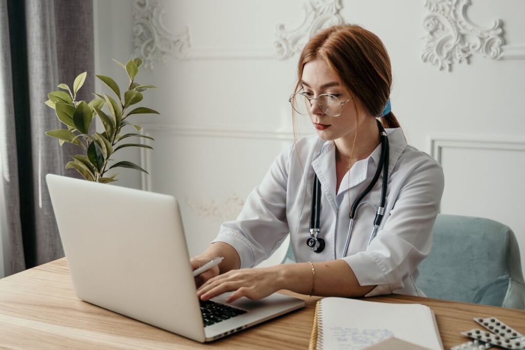 Clinician using a laptop at a desk in a bright office