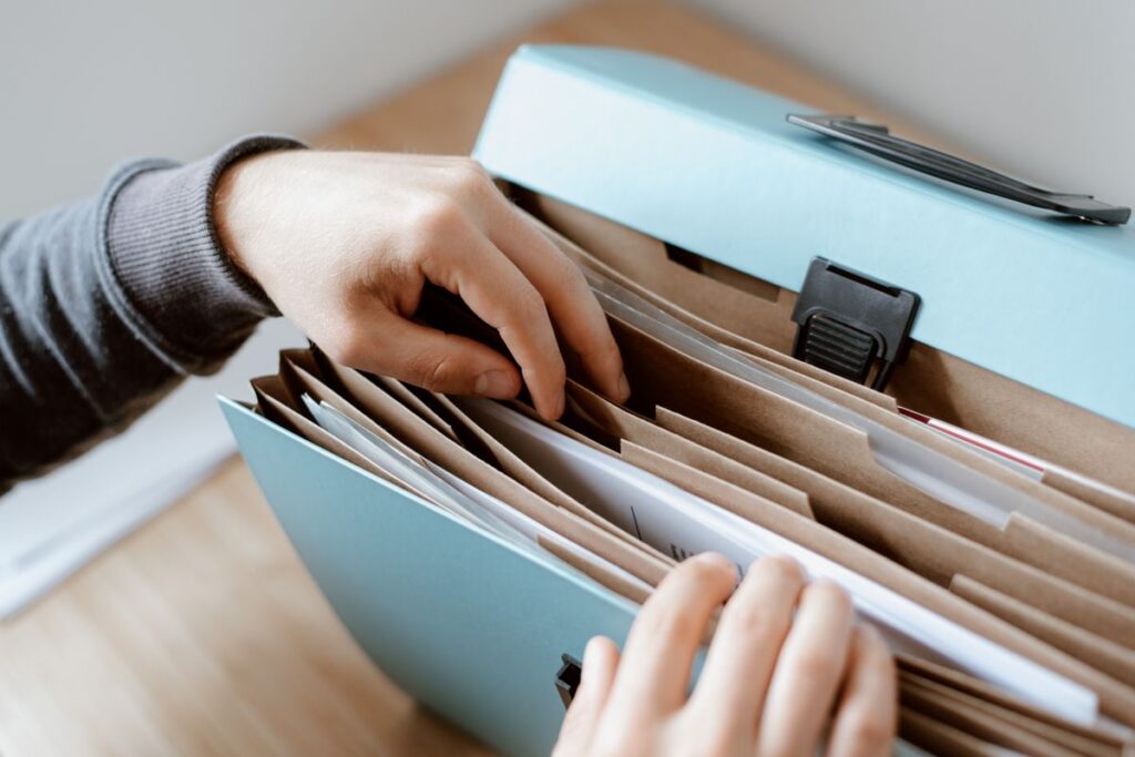 Hands organizing papers in a blue folder on a desk