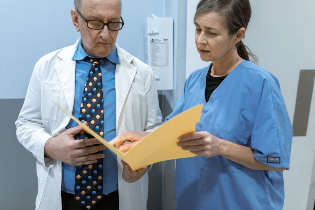 Two healthcare professionals review a folder together in a clinical setting
