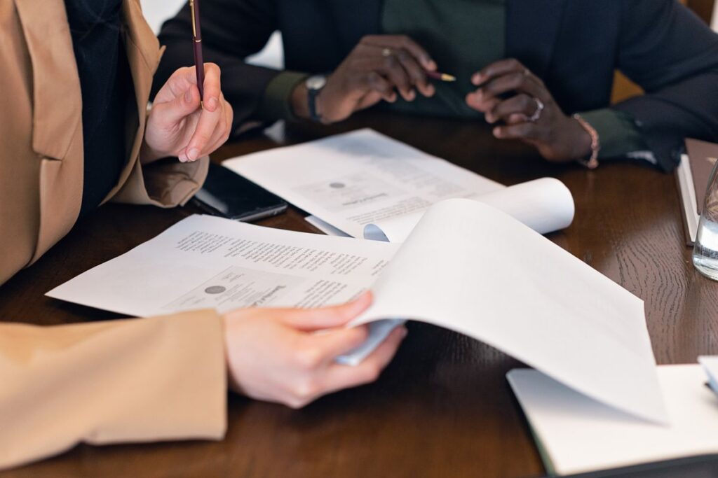 Three professionals compare paperwork together at an office table