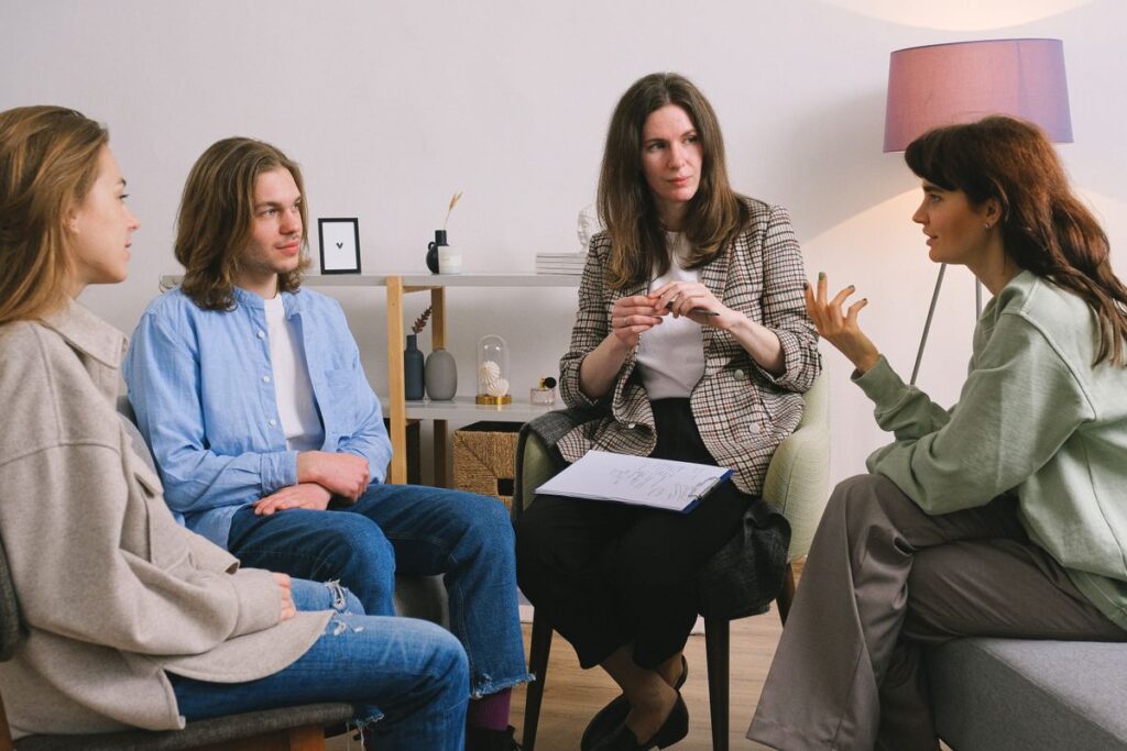 Therapist leads a group discussion while three clients sit together