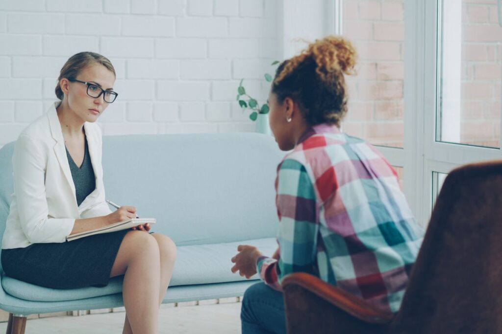 Therapist listens and takes notes while a client speaks during a counseling session