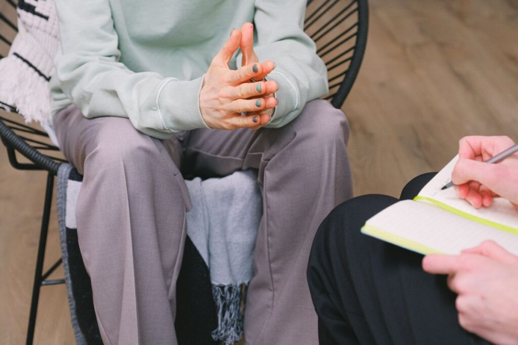 Therapist writes in a notebook while a client sits nearby during counseling